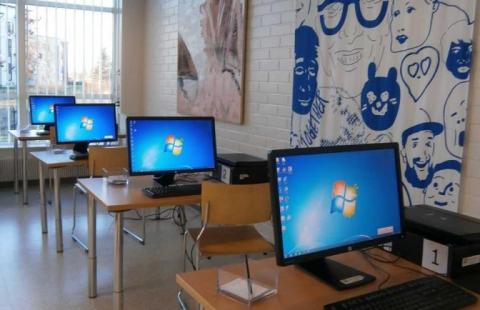 Neljä tietokonetta jonossa omilla pöydillään pääkirjastossa